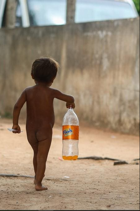 Criança Yanomami carrega garrafa de refrigerante que ganhou em Boa Vista. Foto: Flávio Tavares/O Tempo