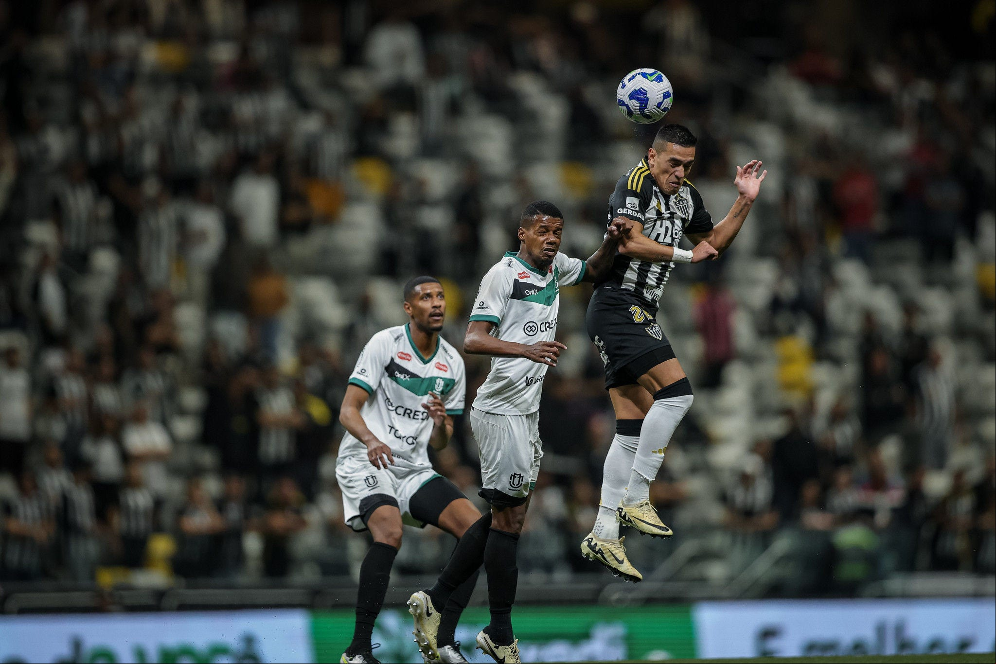 Cuello salta para tentar disputar a bola com defensor do Maringá durante partida disputada na Arena MRV